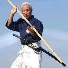 Le Soke maître Hiroo Mochizuki tenant un bâton, le bô en japonais